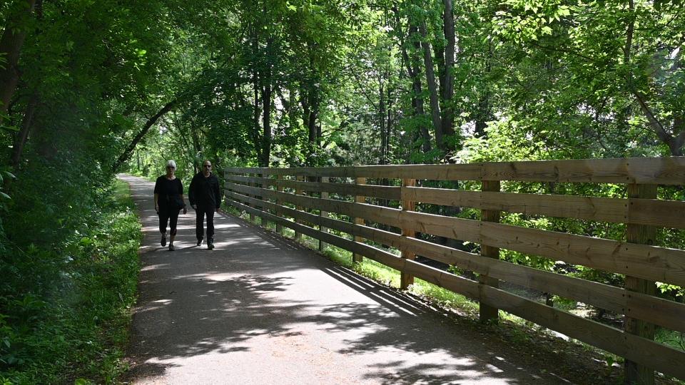couple walking along a tree-lined trail during summer