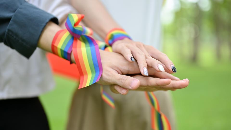Holding hands with pride ribbons on the wrist