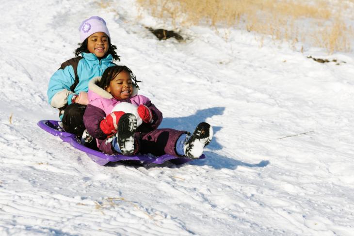 two girls sledding during winter