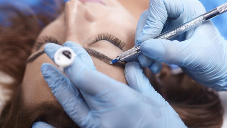 Woman having microblading, a form of body art, performed on her eyebrow.