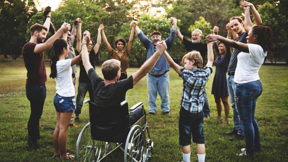 People of all abilities from community holding hands in a unification circle
