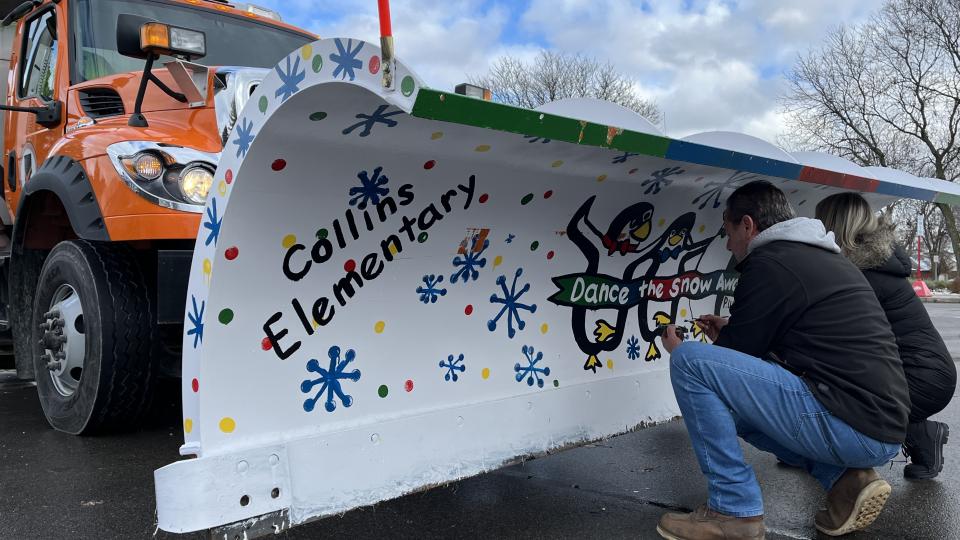 MCDR maintenance personnel and Collins Elementary School art teacher touch up paint on snowplow