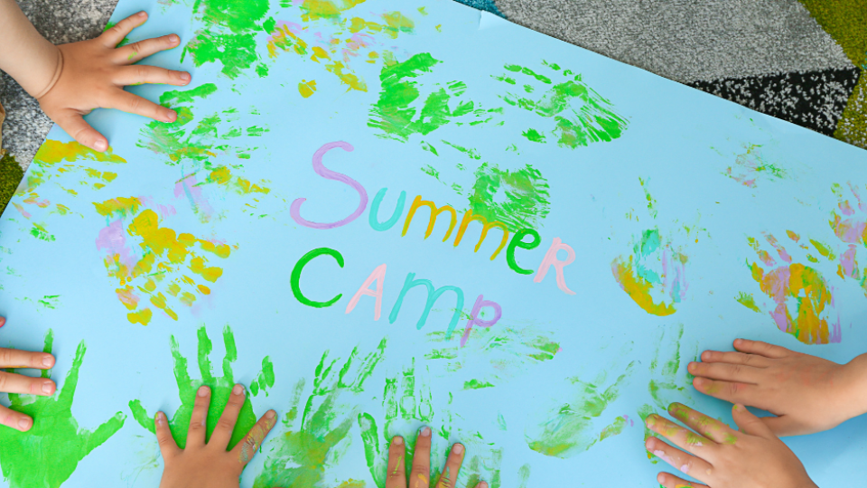 kids hands finger painting on a sign that says summer camp