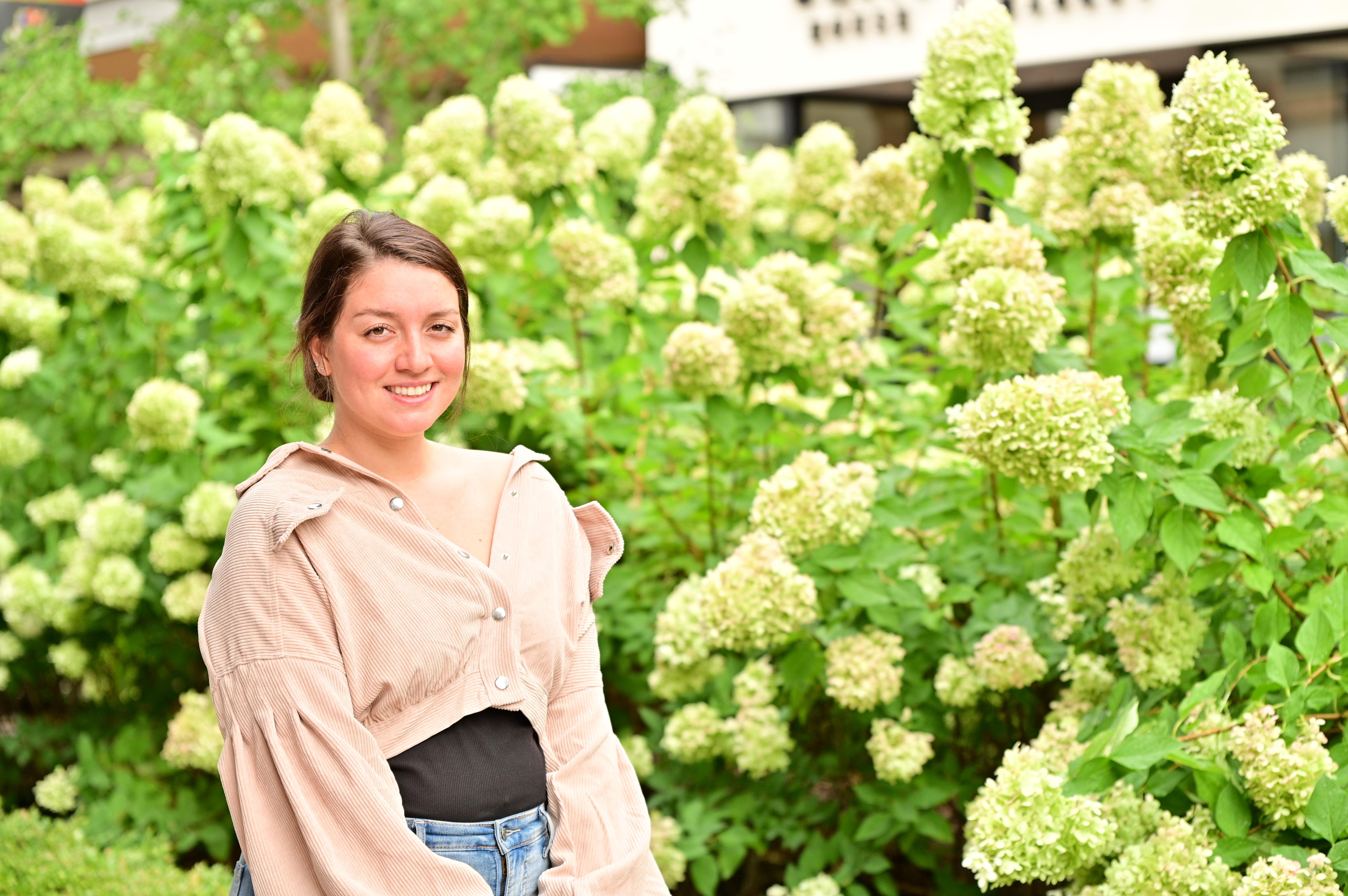 woman stands in front of white hydranga flowers