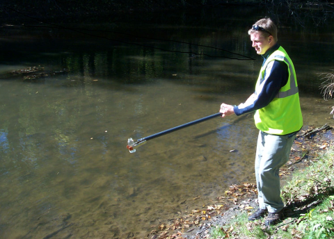 EH staff collecting a water sample from the Clinton River