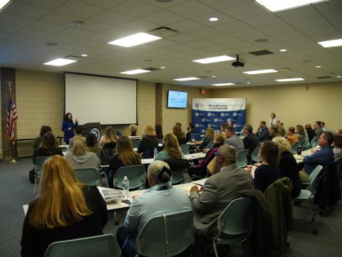 Attorney General Dana Nessel speaking to members of the Macomb County Elder Justice Alliance in a large conference room.