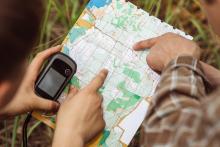 an individual holds a compass and a map for geocaching